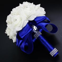 a bridal bouquet with white flowers and blue ribbon on a black background, the bride's brooch