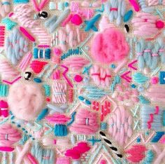 many different types of hair brushes and combs on a white cloth with pink, blue, and green yarn