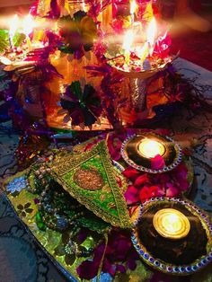 there are many candles that are lit on the table with flowers and other decorations around it