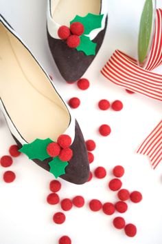 a pair of shoes with holly berry decorations on them and candy scattered around the shoe