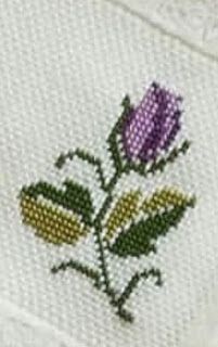 a close up of a flower on a white shirt with green leaves and purple flowers