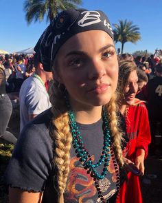 a girl with long braids wearing a bandana and beads at a music festival