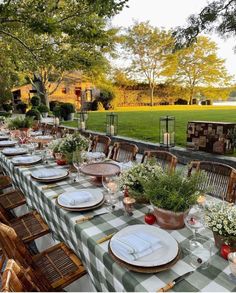 a long table set with place settings and flowers on it for an outdoor dinner party