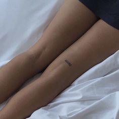 a woman's legs with the word love tattooed on her left leg, laying in bed