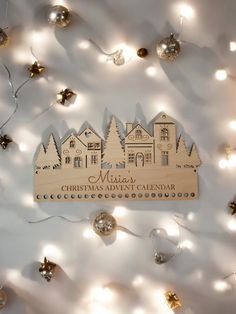 a wooden christmas ornament hanging on a wall with lights and decorations around it