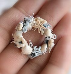 a hand holding a ring made out of seashells and starfish