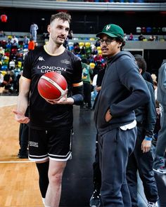 two men standing next to each other with a basketball in their hands on a court