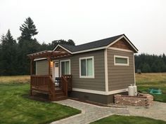 a small house with a porch and deck in the front yard on a cloudy day