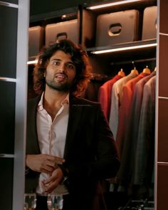 a man standing in front of a closet full of clothes