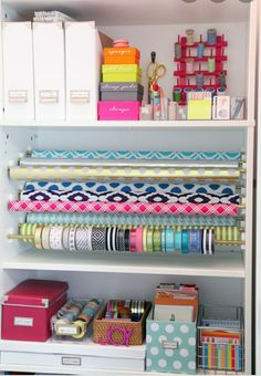 an organized closet with lots of crafting supplies and wrapping paper on the shelve