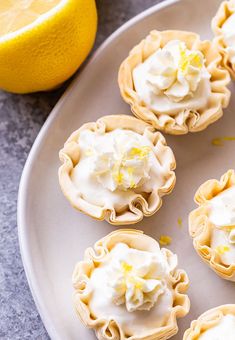 lemon meringue tarts on a white plate next to a lemon