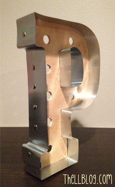 a metal letter that is on top of a wooden table and has holes in it