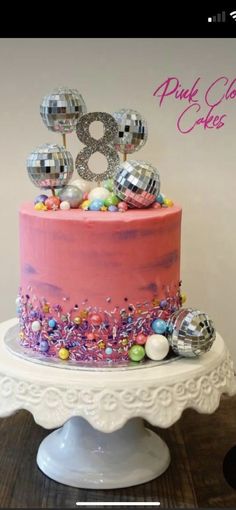 a pink cake with silver decorations on top and the number eight on it's side