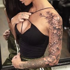 a woman with tattoos on her arm and shoulder is looking at herself in the mirror