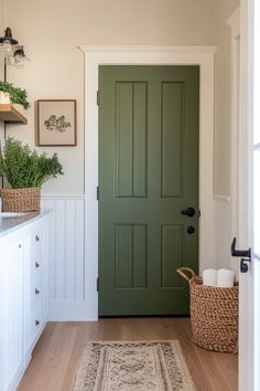 a green door in a white kitchen next to a basket with plants on the wall