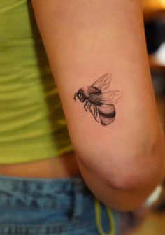 a woman's arm with a small tattoo of a bee on the back of her arm