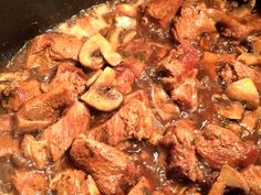 meat and mushrooms are being cooked in a skillet