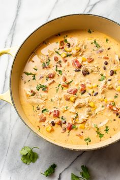 a large pot filled with soup and garnished with cilantro, black beans, corn, and parsley