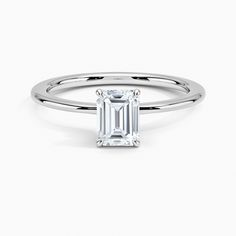 an emerald cut engagement ring with a thin band on the side and a diamond in the center