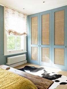 a bed room with a neatly made bed next to a sliding glass door and a cow rug