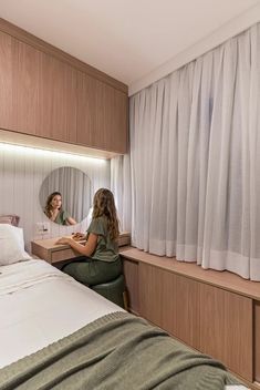 two women sitting at a bed in a room with curtains on the window sill