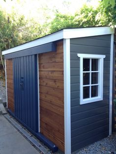 a small shed with a window on the side and sidings painted blue, brown and white