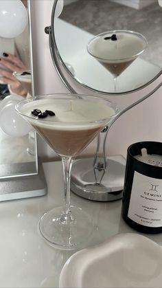 a martini sitting on top of a white counter next to a mirror and a candle