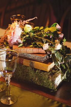 an arrangement of books and flowers on a table