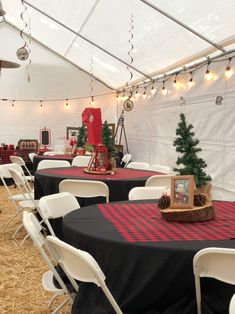 tables and chairs are set up in a tent for an outdoor christmas party with lights strung from the ceiling