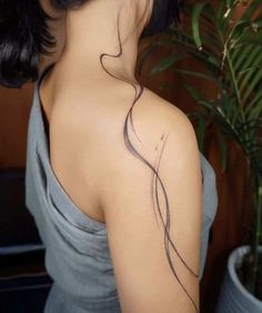 the back of a woman's neck with a tattoo on it, in front of a potted plant