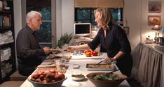 two people standing at a kitchen counter preparing food