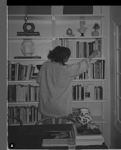 a woman standing in front of a book shelf filled with books