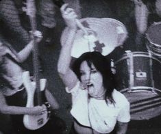 the woman is singing into her microphone while playing guitar in front of two other people