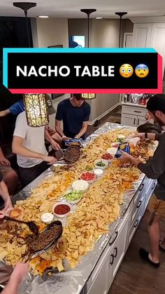 a table filled with lots of food and people standing around it