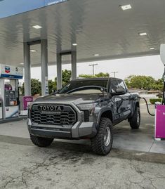 a truck is parked in front of a gas station with an electric charger attached to it