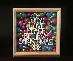 a wooden frame filled with christmas ornaments and the words joy love peace believe christmas written in white