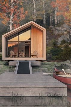 a small cabin sits on the edge of a body of water with two canoes nearby