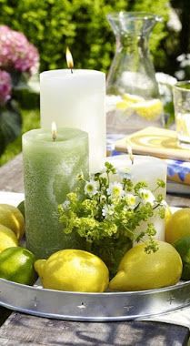 a table with lemons, limes and candles on it in a metal bowl