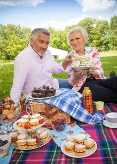 two people sitting at a picnic table with food and drinks