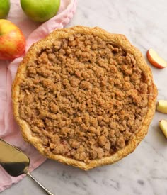 an apple pie sitting on top of a table next to sliced apples and a spoon