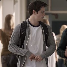 two young men standing next to each other in front of a building with people walking around