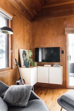 a living room filled with furniture and a flat screen tv on top of a wooden wall