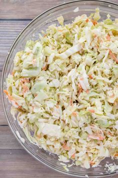 a glass bowl filled with coleslaw on top of a wooden table