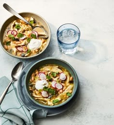 two bowls filled with food next to a glass of water