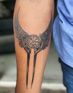 a person with a tattoo on their arm holding a knife and compass in the shape of wings