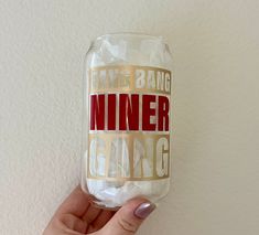 a person holding up a wine glass with the words inner caring printed on it, in front of a white wall