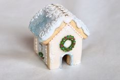 a small white gingerbread house with a wreath on top