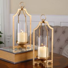 two candles sitting on top of a wooden table next to a book and glass container