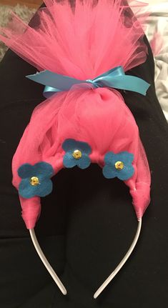 a pink headband with blue flowers and tulle on the side, sitting on top of a black surface