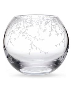 an empty glass bowl with white flowers on the bottom and branches in the middle, set against a white background